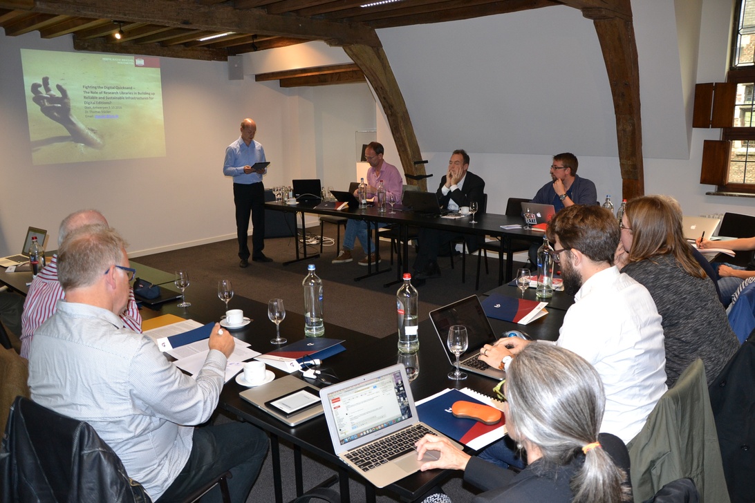 Eine professionelle Konferenzsitzung mit einem Präsentator vor einer Projektionswand. Teilnehmer sitzen an Tischen mit Laptops, Wasserflaschen und Konferenzmaterialien. Die Einrichtung demonstriert Raumaufteilung, Technologieintegration und Erfrischungsbereitstellung als Schlüsselelemente der Konferenzlogistik.